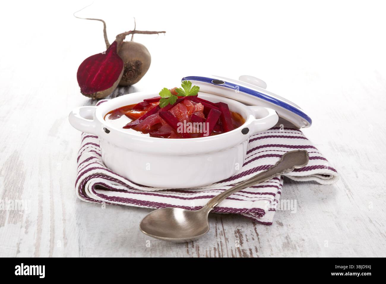 Deliziosa zuppa borsch ucraina con verdure fresche di barbabietola su un panno viola su un tavolo rustico in legno. Cucina tradizionale europea Foto Stock