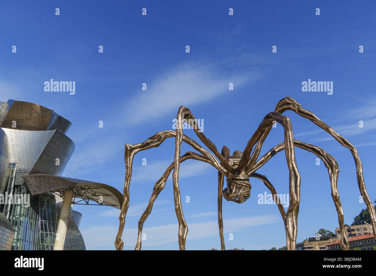 Scultura di ragno metallizzata accanto a un edificio moderno contro un cielo blu, Bilbao, Paesi Baschi, Spagna, Europa Foto Stock