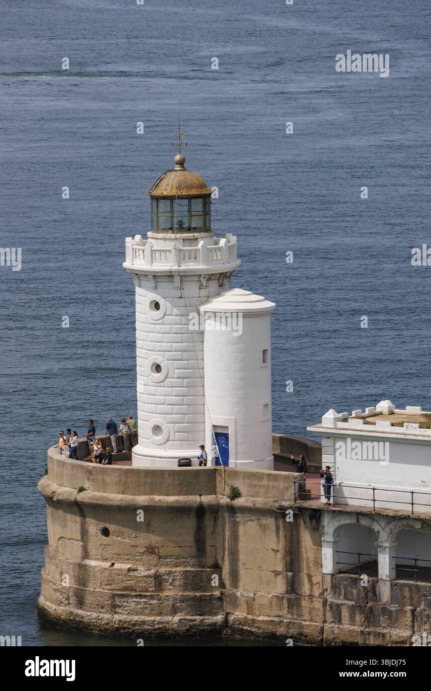 Faro con visitatori su un muro di pietra che si affaccia sul mare, Gexto, Paesi Baschi, Spagna, Europa Foto Stock