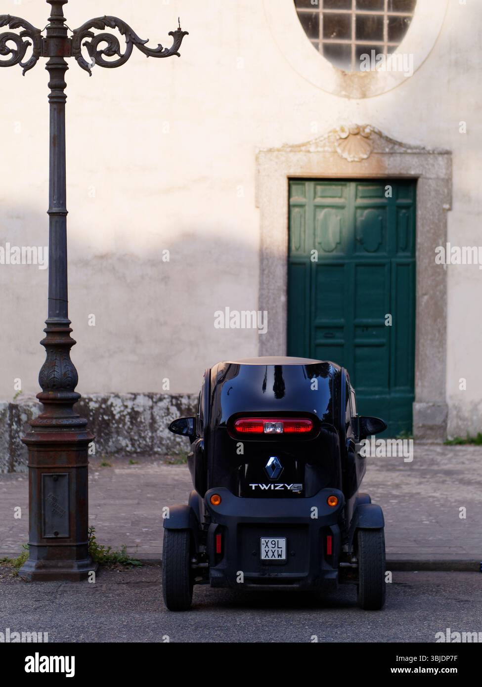 Minuscola auto nera Renault Twizy parcheggiata dallo storico lampione dietro la chiesa di San Flaviano a Montefiascone, Italia. 14 giugno 2025. Foto Stock
