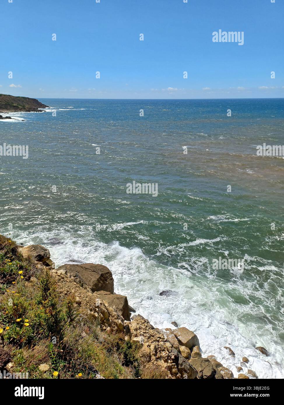 Costa frastagliata e scogliere rocciose di São Martinho do Porto Portogallo con onde che si infrangono e viste panoramiche dell'oceano sotto un vivace cielo blu Foto Stock