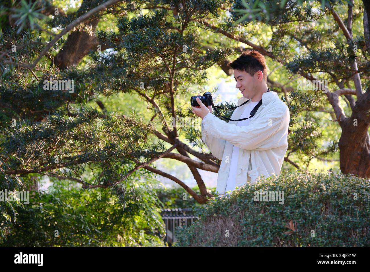 il giovane scatta foto con la fotocamera mirrorless in primavera Foto Stock