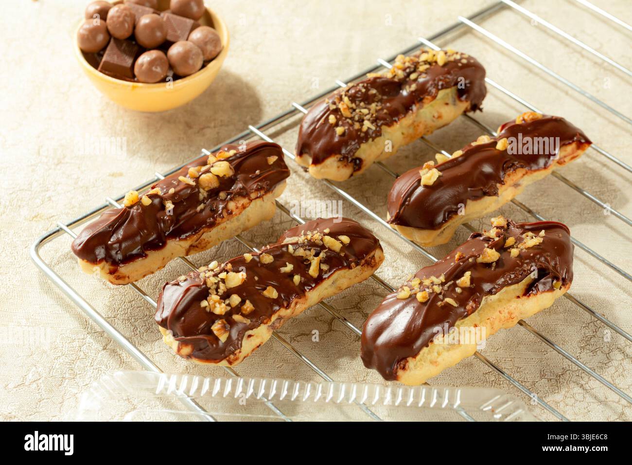 Dessert éclair di prima qualità con cioccolato al latte e noci, isolato su sfondo bianco. Foto Stock
