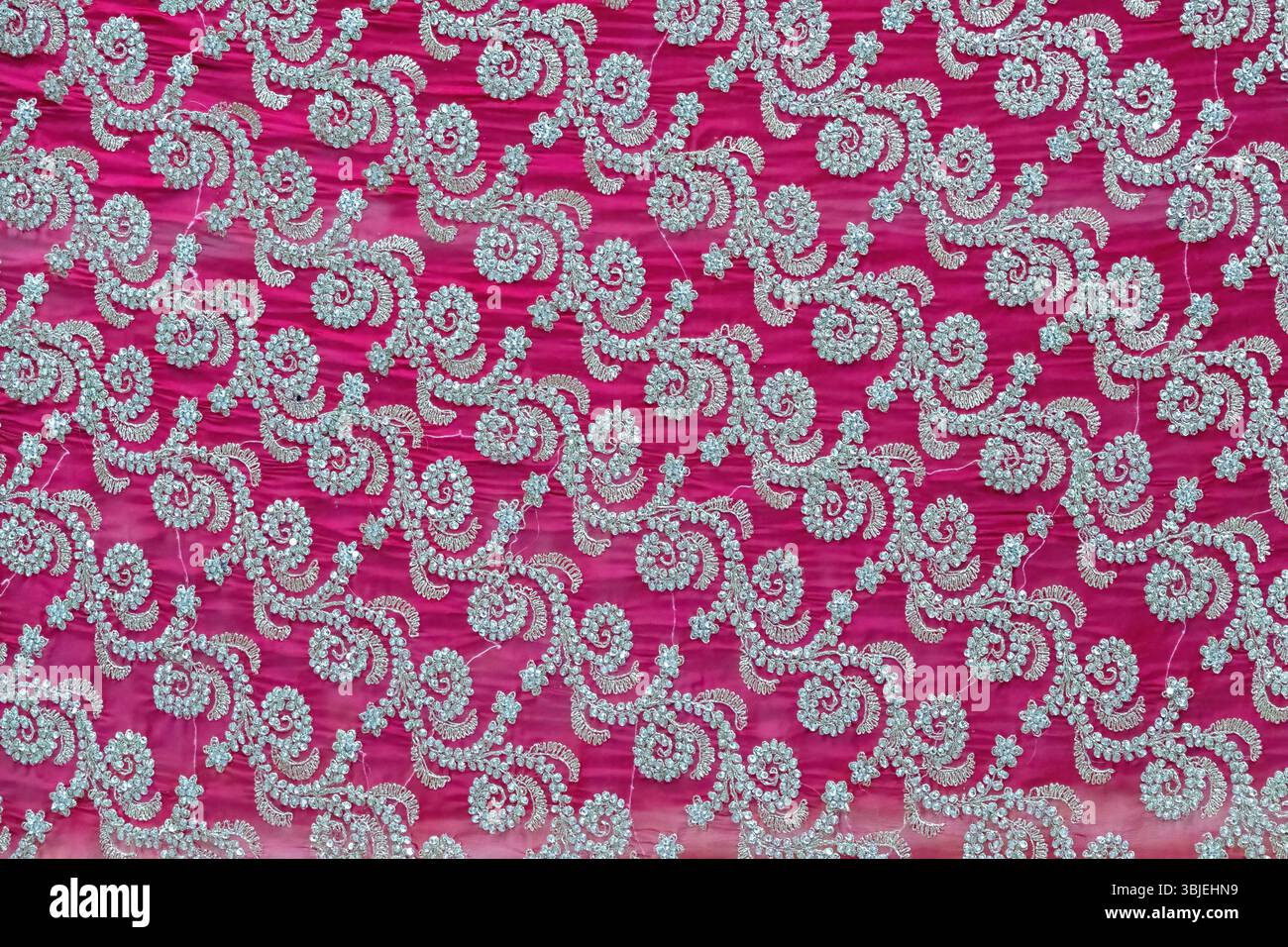 Motivo floreale su tessuto in georgette sari rosa scuro con ricami a perline. Elegante sfondo in tessuto. Foto Stock