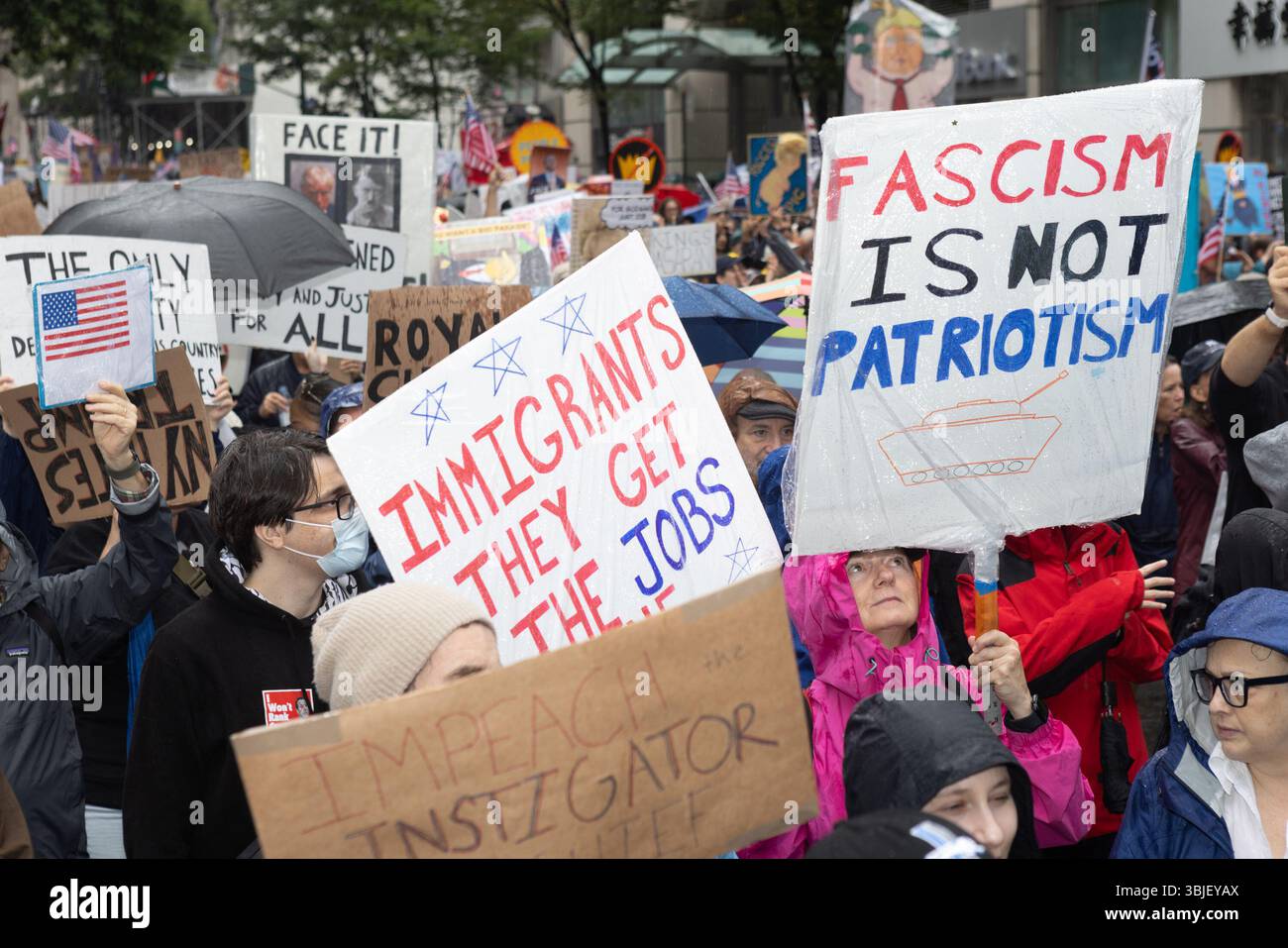 New York, Stati Uniti. 14 giugno 2025. I manifestanti marciano con cartelli per le strade sotto la pioggia durante la protesta "No Kings Day". La gente ha colpito le strade a livello nazionale per marciare contro il presidente Trump e la sua amministrazione aumentando il dominio autocratico. Il presidente ha celebrato il suo compleanno, che è il 14 luglio, ospitando una parata che espone le forze armate del paese. Credito: SOPA Images Limited/Alamy Live News Foto Stock