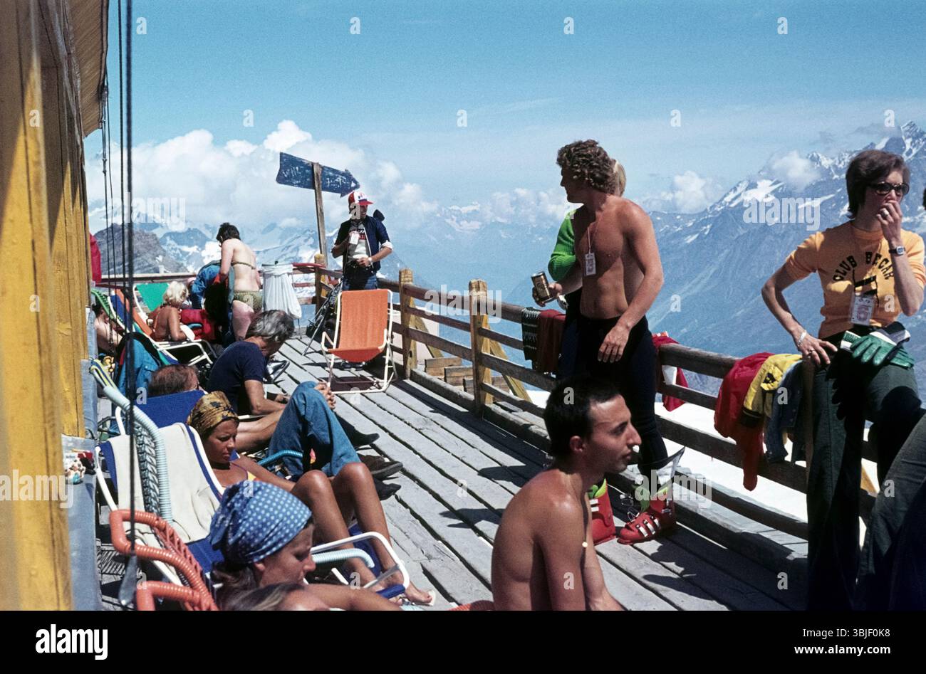Gli escursionisti e gli sciatori prendono il sole sulla terrazza del Rifugio testa Grigia in una calda giornata estiva. Rifugio Guide del Cervino, Italia/Svizzera, 1975 Foto Stock