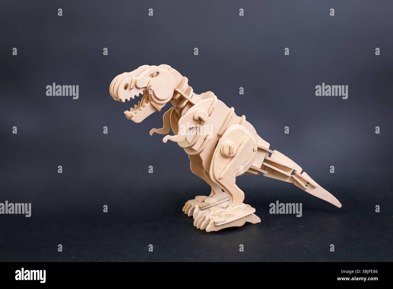 Puzzle in legno di dinosauro isolato su sfondo scuro, con spazio di copia Foto Stock