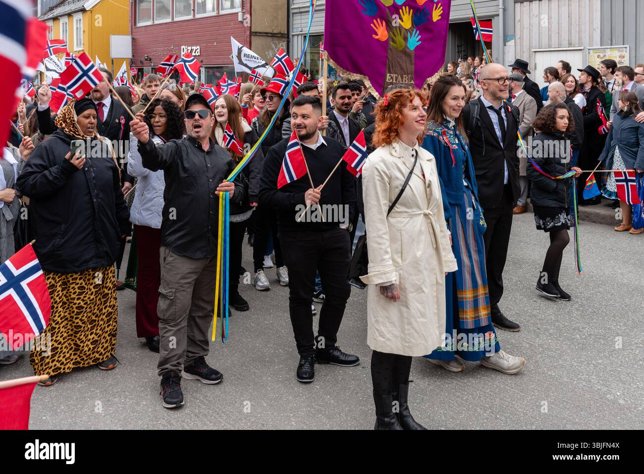 Tromso, Norvegia. Una varietà di persone che camminano per le strade sventolando bandiere norvegesi per celebrare la Festa della Costituzione norvegese (syttende mai) il 17 maggio Foto Stock