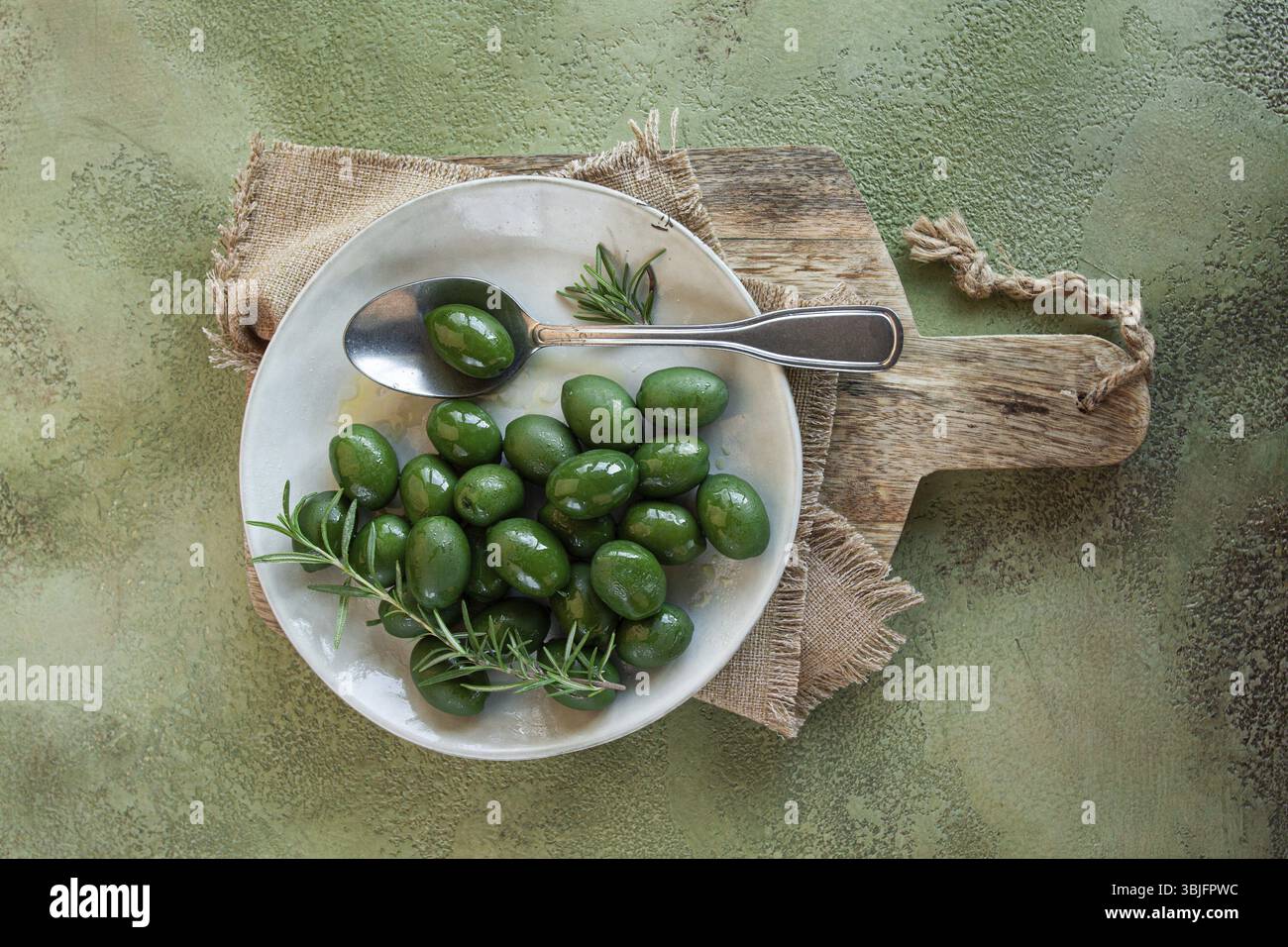 Olive calcidica, classiche olive verdi greche, su un piatto, con un cucchiaio, vista dall'alto, niente persone Foto Stock