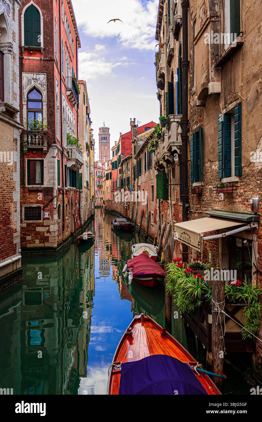 in un canale tranquillo le gondole sono parcheggiate, mentre i turisti visitano la città Foto Stock