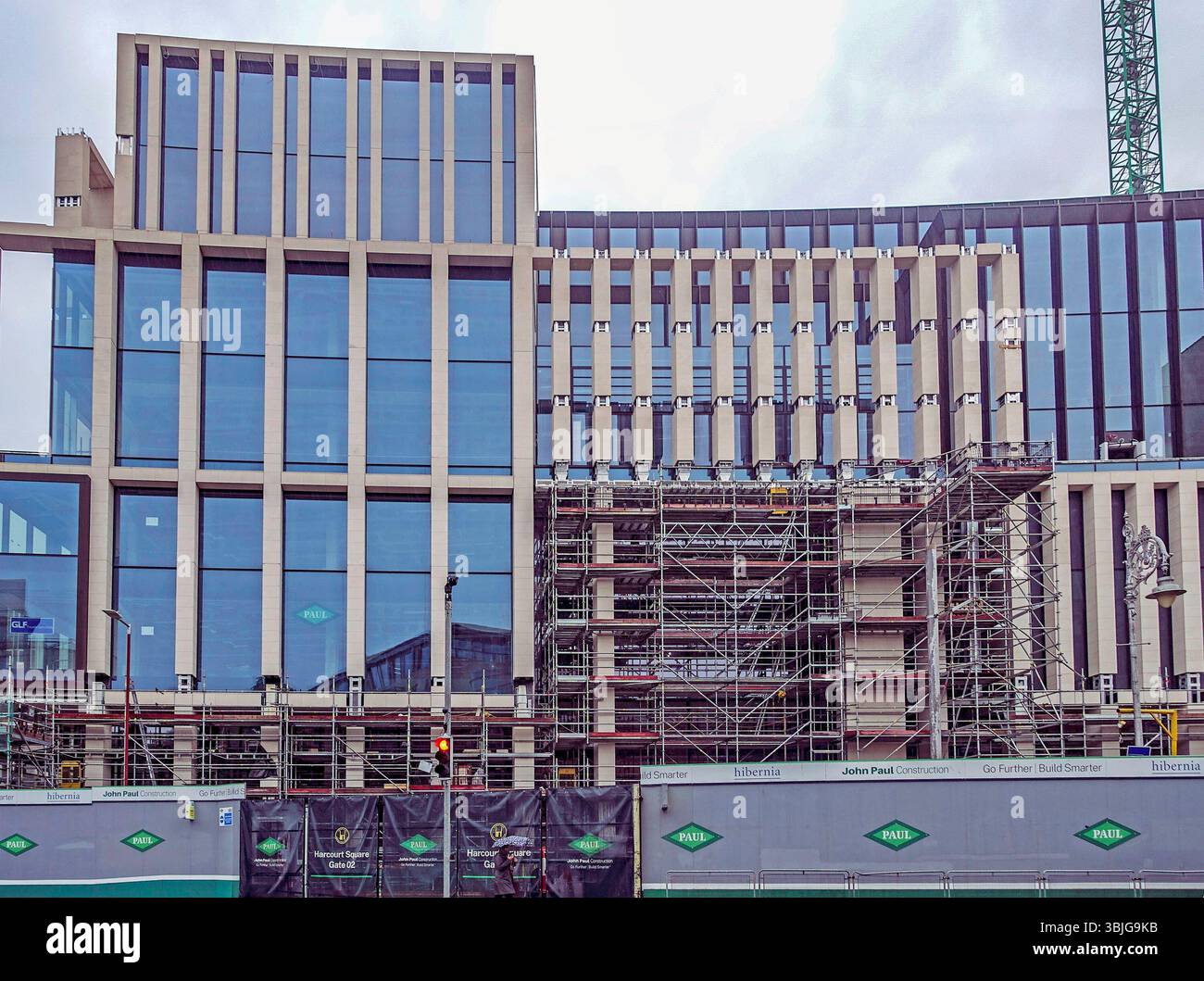 Sviluppo moderno di uffici in costruzione in Harcourt Street, Dublino, Irlanda, con facciata in vetro, ponteggi, e la segnaletica della John Paul Construction. Foto Stock