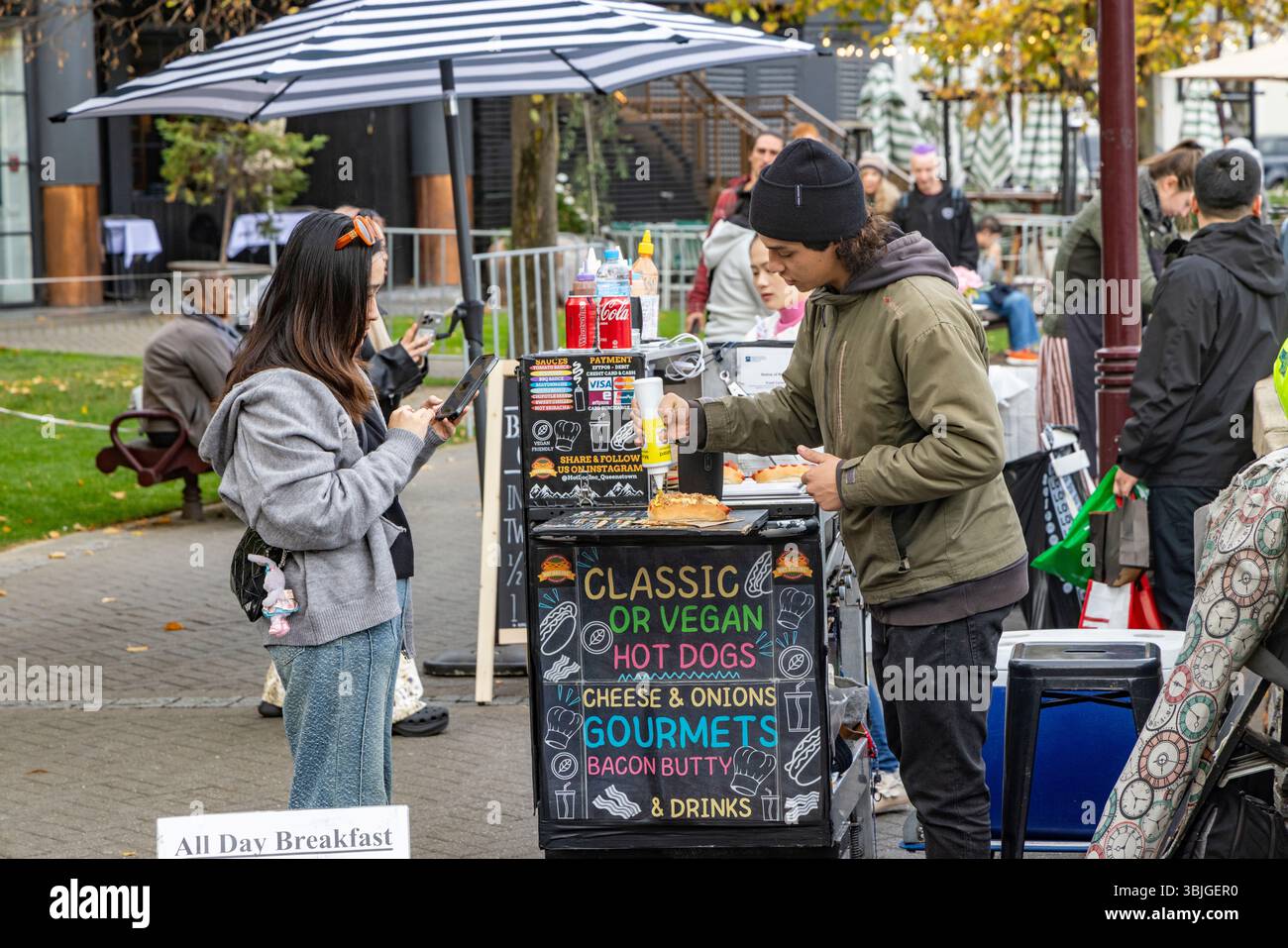 Venditrice di cibo di strada sulla passeggiata del molo di Queenstown che vende frankfurter, hot dog classici e hot dog vegani e bacon butty, regione di Otago, nuova Zelanda Foto Stock