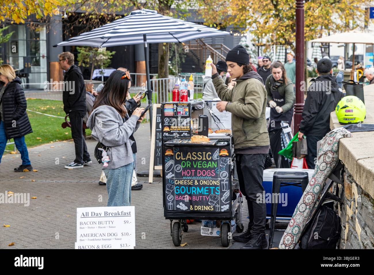 Venditrice di cibo di strada sulla passeggiata del molo di Queenstown che vende frankfurter, hot dog classici e hot dog vegani e bacon butty, regione di Otago, nuova Zelanda Foto Stock
