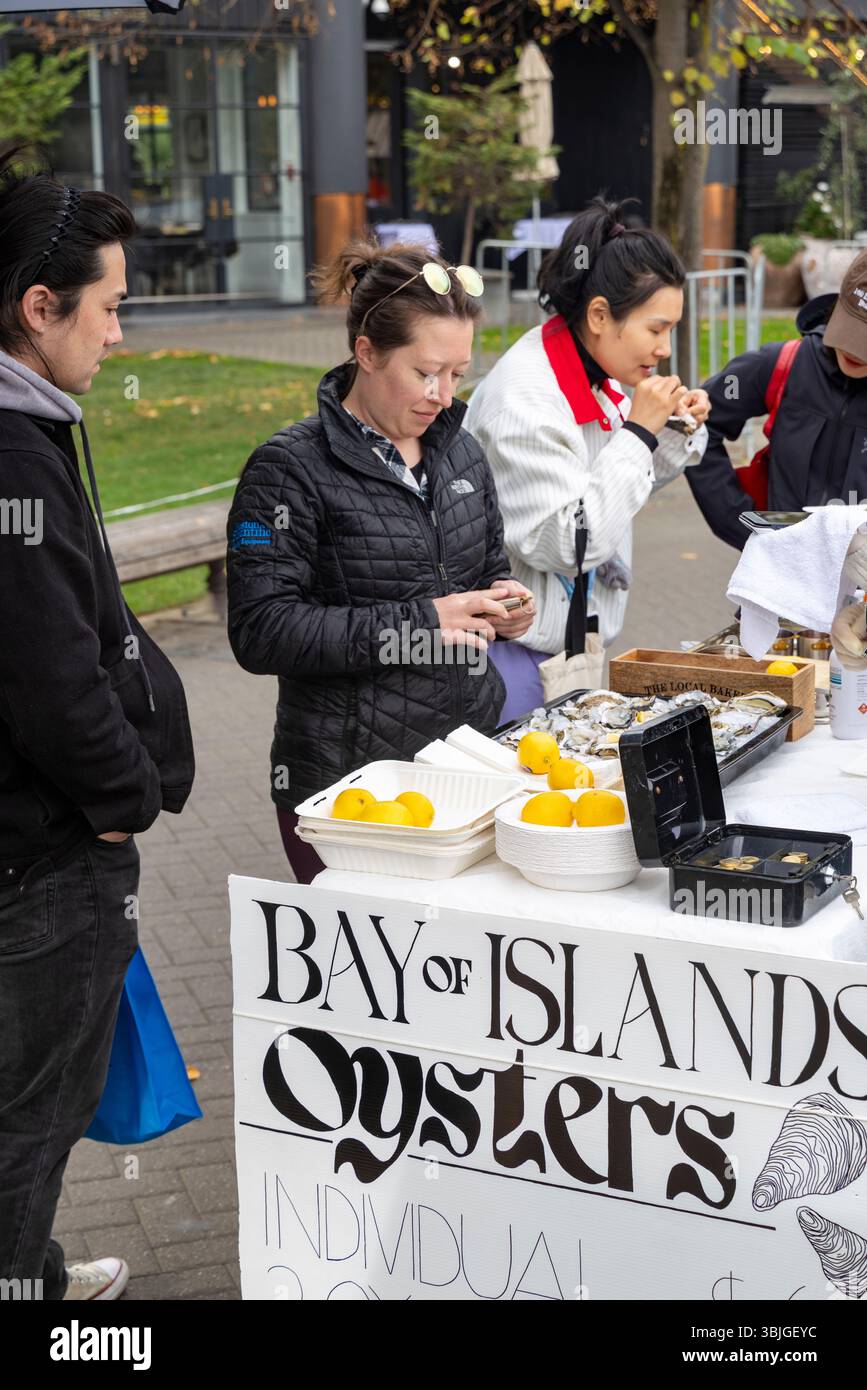 Lady che vende le ostriche fresche di strada della Bay of Islands sulla passeggiata al molo di Queenstown, nella regione di Otago, nell'Isola del Sud, in nuova Zelanda Foto Stock