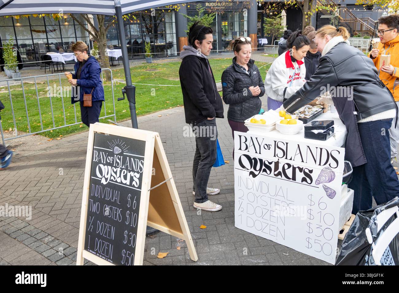 Lady che vende le ostriche fresche di strada della Bay of Islands sulla passeggiata al molo di Queenstown, nella regione di Otago, nell'Isola del Sud, in nuova Zelanda Foto Stock