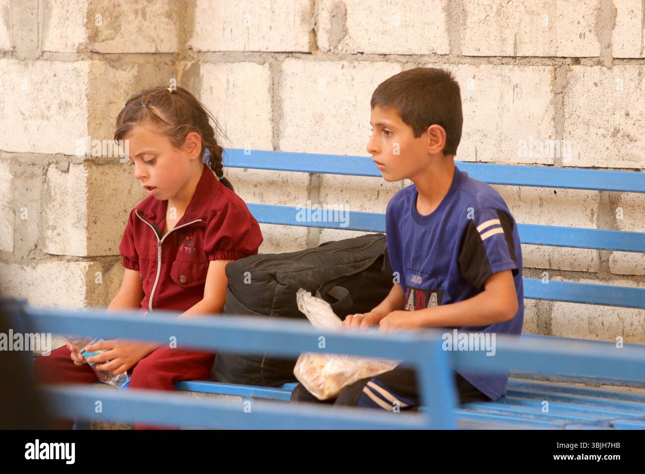 Al Hasakah. 16 giugno 2025. Due bambini riposano su una panchina mentre vengono evacuati dal campo di al-Hol nella provincia nord-orientale della Siria di al-Hasakah, il 15 giugno 2025. Decine di famiglie siriane sfollate hanno lasciato il famigerato campo di al-Hol nella Siria nord-orientale domenica, in un trasferimento umanitario coordinato tra l'amministrazione autonoma curda e il governo ad interim siriano, confermato da un coordinatore. Crediti: Str/Xinhua/Alamy Live News Foto Stock