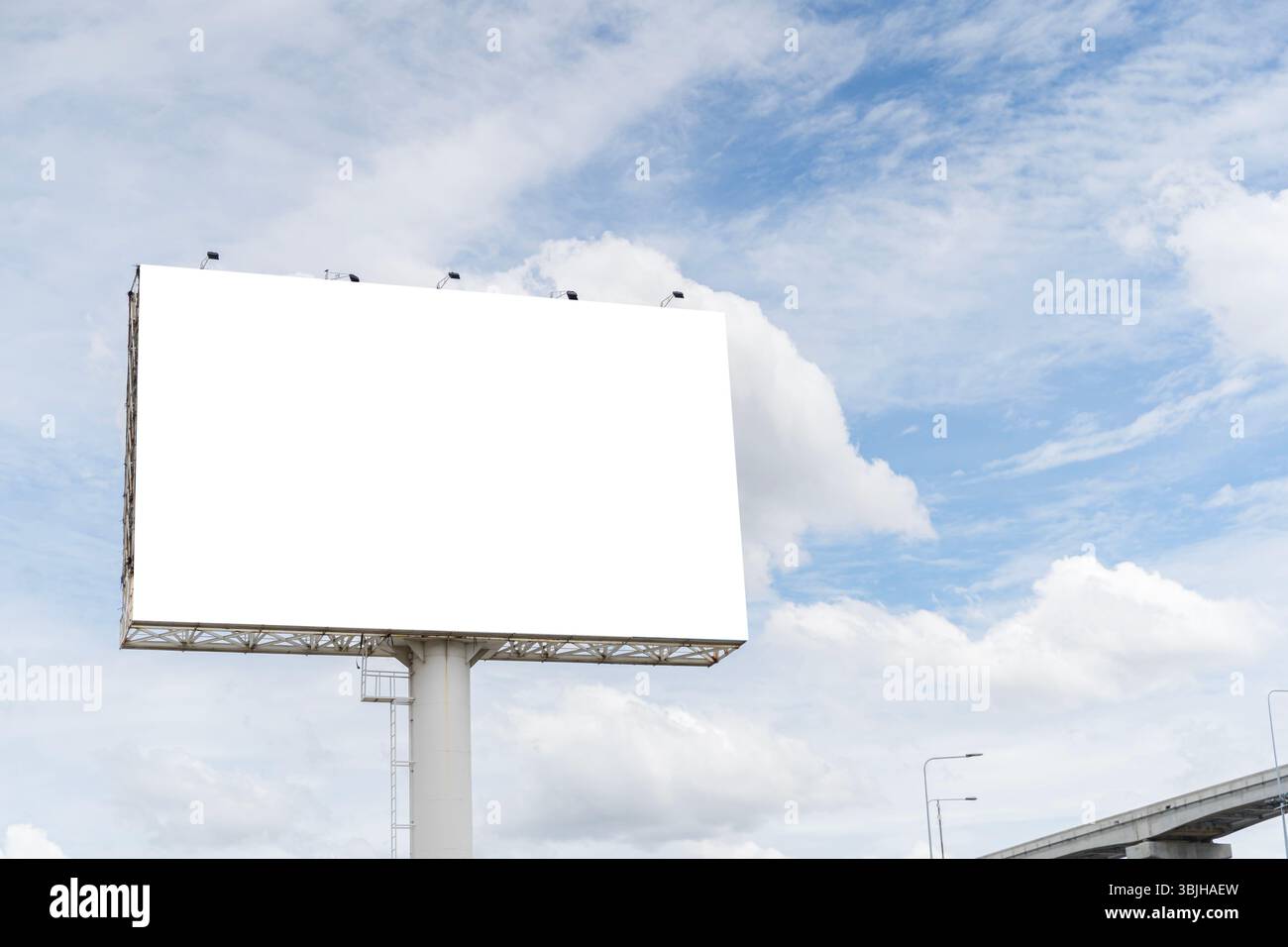 Grande cartellone bianco vuoto con cielo luminoso e sfondo nuvoloso. Modello di mockup ideale per pubblicità all'aperto, design di marketing, presentazione di annunci Foto Stock