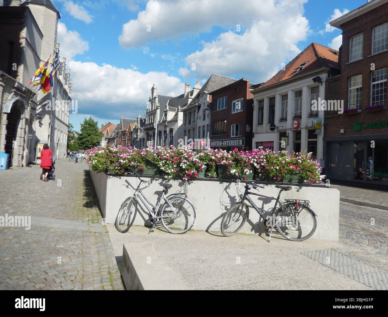 Affascinante strada europea con biciclette e fiori colorati in una giornata di sole. Mechelen, Belgio Foto Stock