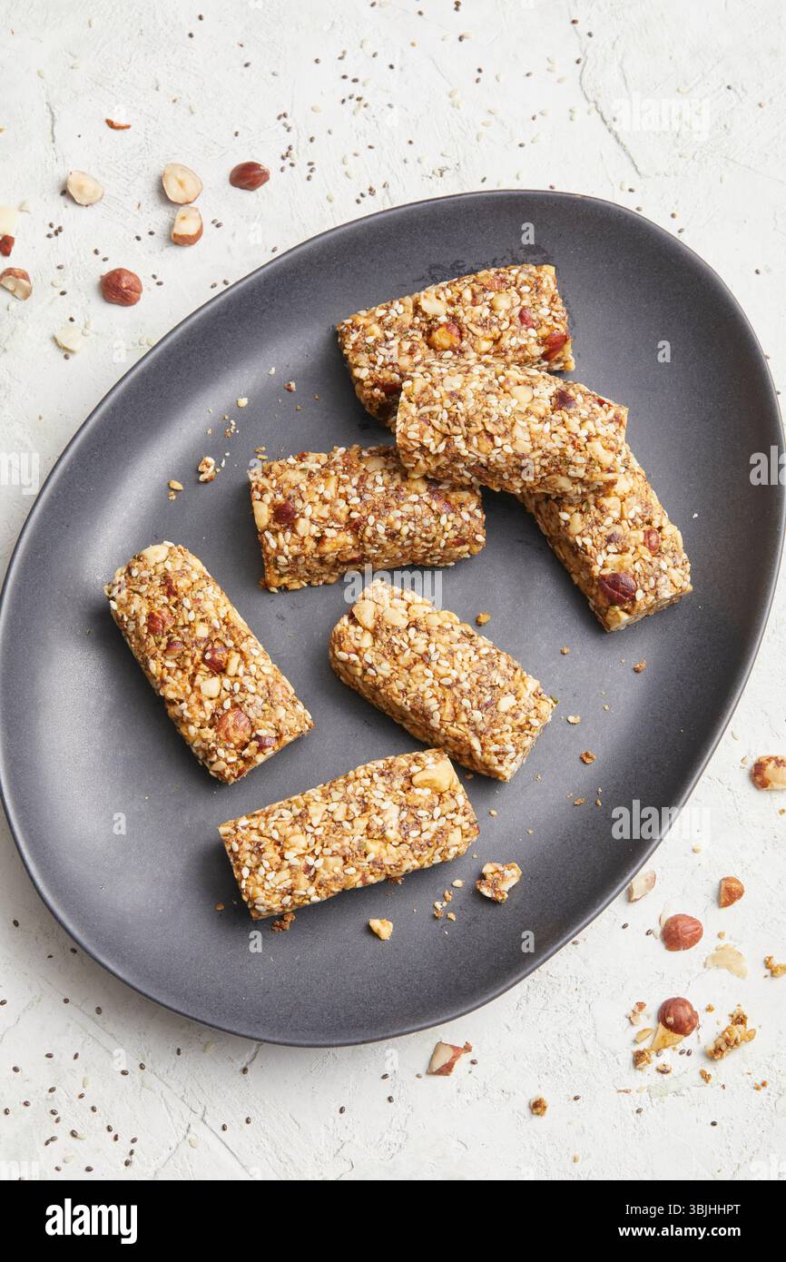 Barrette di noci su un piatto ovale grigio scuro: Un'idea sana e croccante a base vegetale, perfetta per mangiare in modo pulito, preparare i pasti o nutrirsi in movimento. Foto Stock