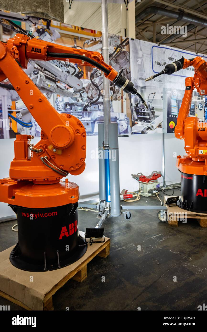 Ucraina, Kiev - maggio 27, 2025:Orange Industrial Robotic Arms in mostra alla fiera che sottolinea l'innovazione e l'avanzamento tecnologico negli automati Foto Stock