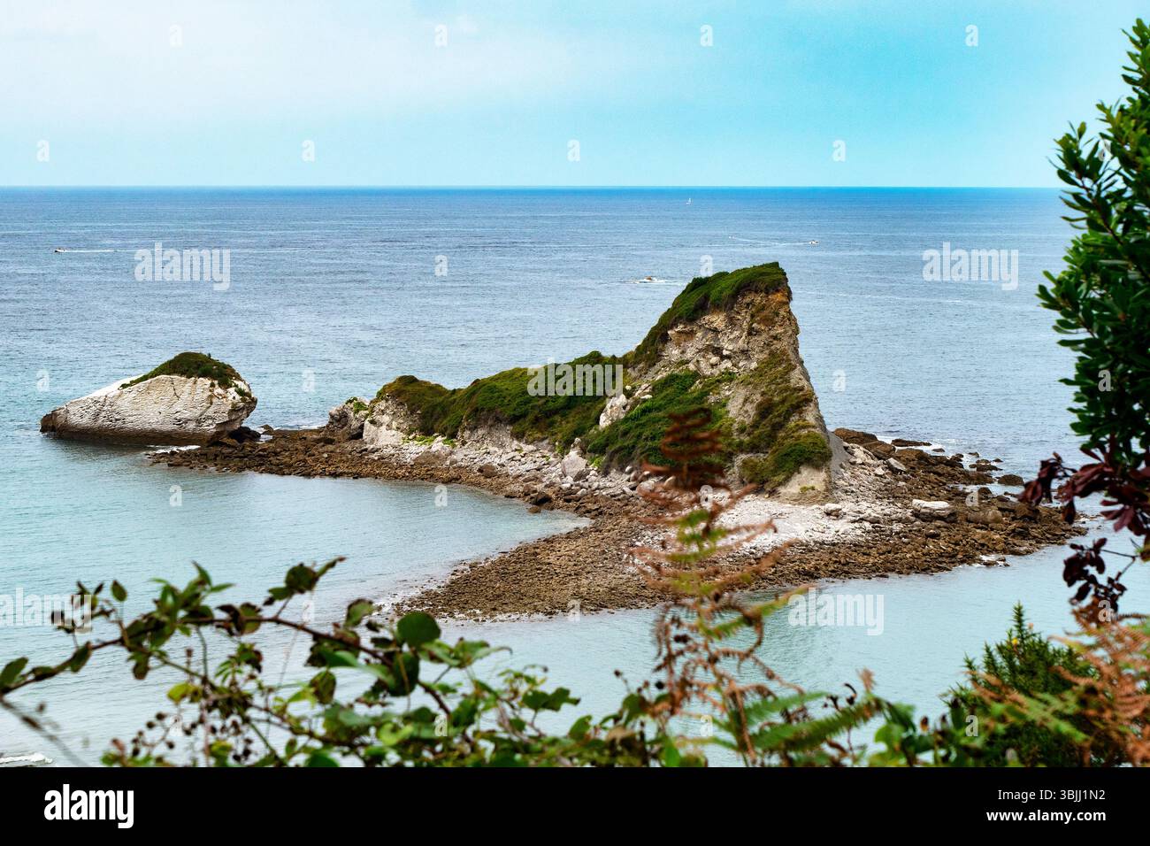 Un'isola rocciosa si trova in mezzo all'oceano. L'acqua è calma e il cielo è limpido, Saint jean de Luz, Francia Foto Stock