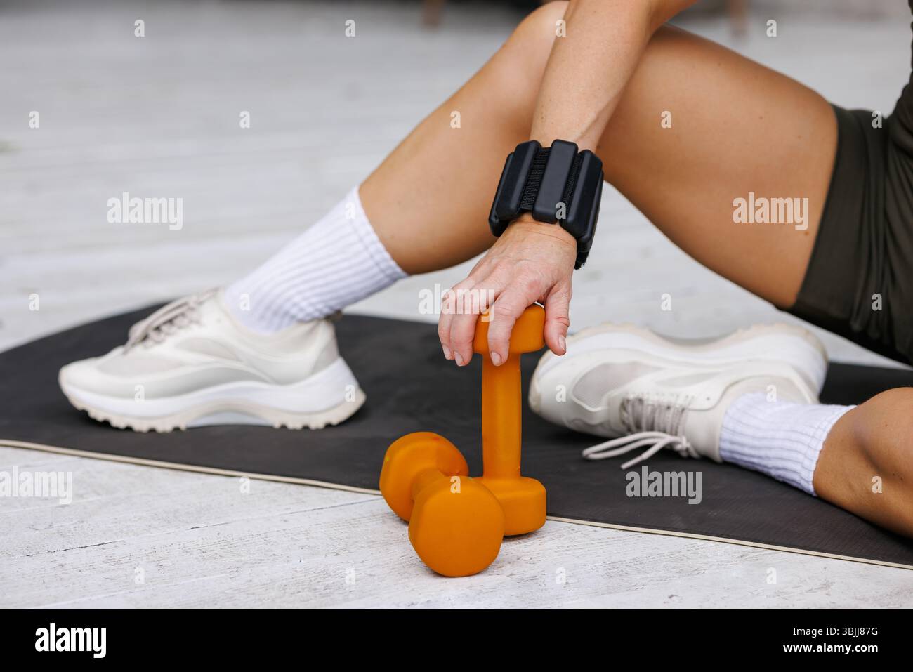 Manichino arancione, scarpe da ginnastica bianche, pesi da polso e tappetino per yoga all'aperto, concentrandosi sul fitness, la forza e lo stile di vita attivo. Foto Stock