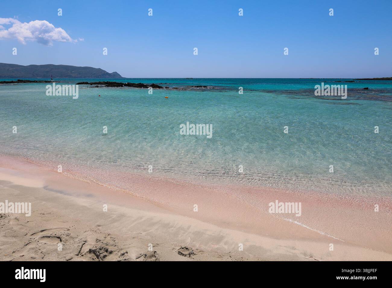 Sabbia rosa e acqua turchese sulla spiaggia di Elafonissi, Creta, Grecia. Un paesaggio marino estivo da sogno con tonalità pastello, cielo limpido e calda luce mediterranea Foto Stock