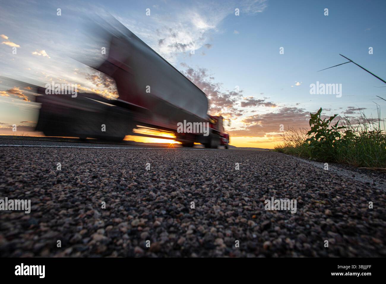 Angolo basso su strada, veicolo sfocato in transito Foto Stock