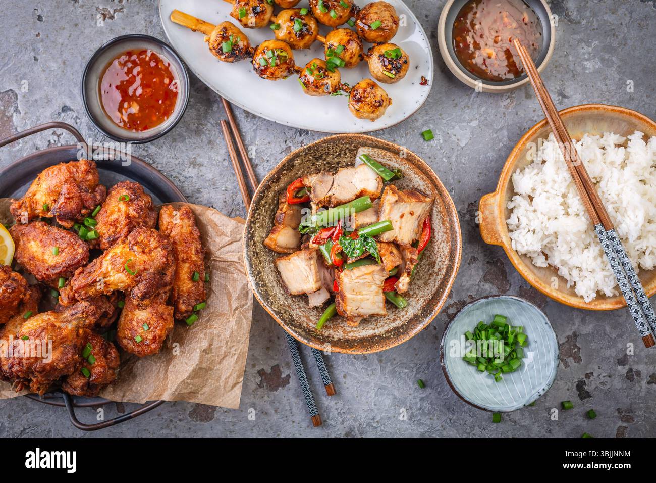 Assortimento di Street food asiatici, frittura in padella con verdure, ali di pollo, polpette di carne e riso Foto Stock
