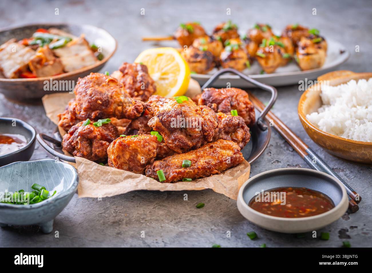 Assortimento di Street food asiatici, frittura in padella con verdure, ali di pollo, polpette di carne e riso Foto Stock