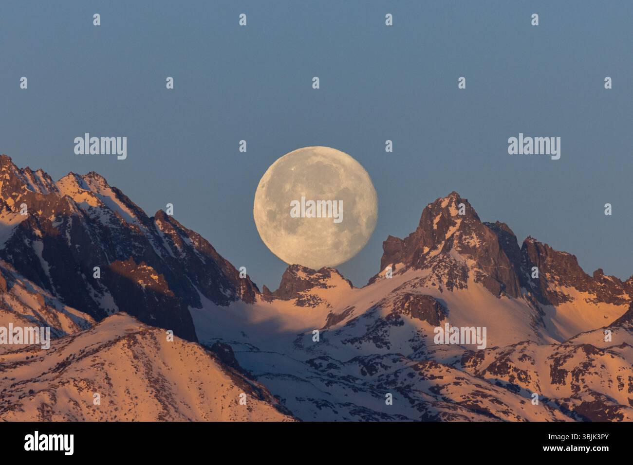 La luna piena sulle cime innevate della catena montuosa della Sierra Nevada. Foto Stock
