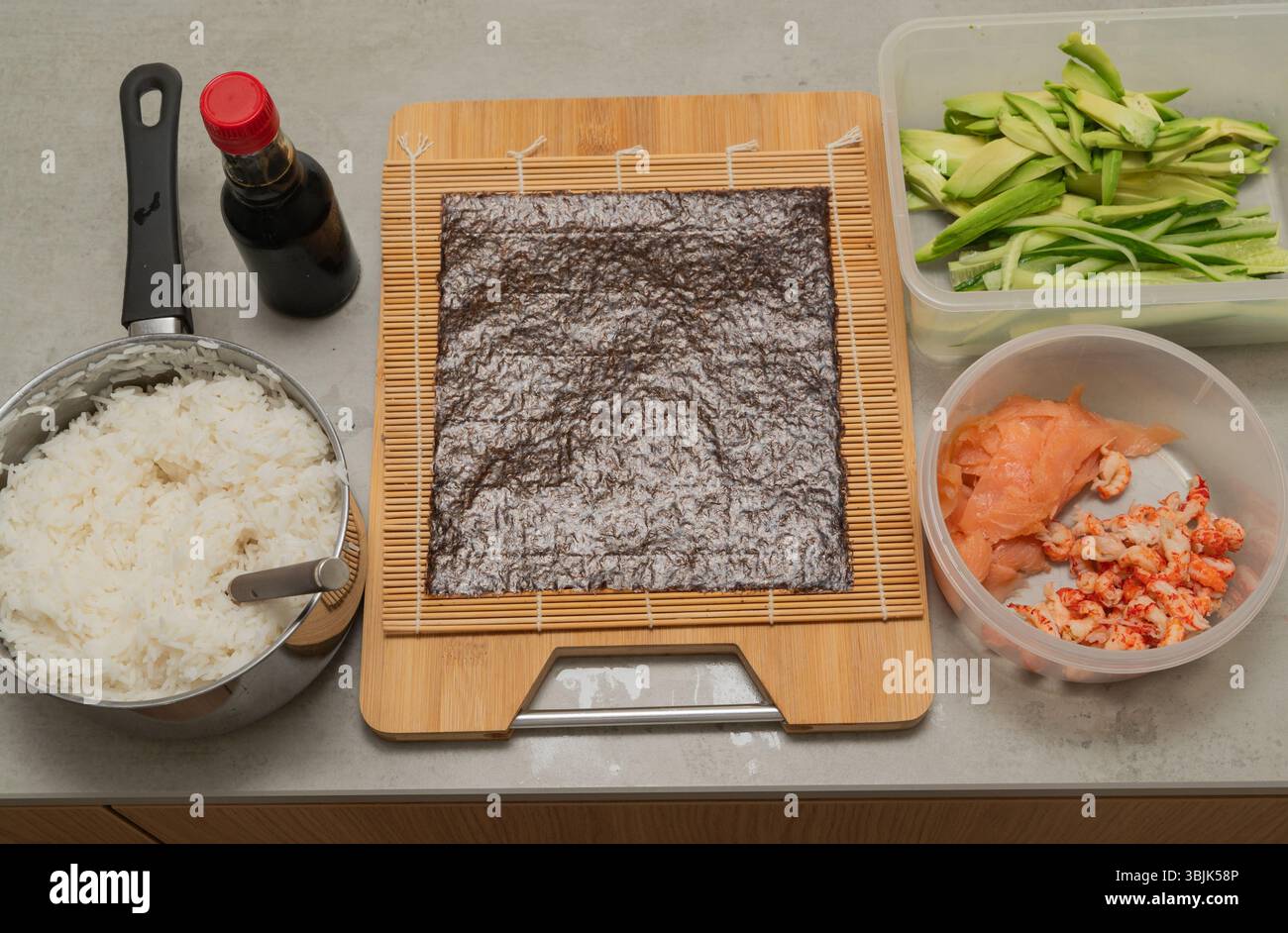 Gli ingredienti per il sushi e gli utensili essenziali sono ben disposti sul bancone della cucina Foto Stock