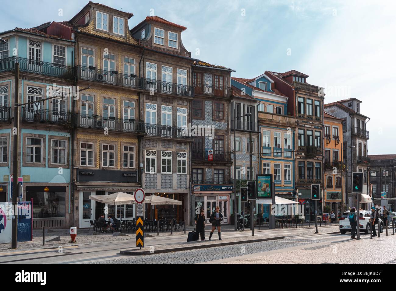 Vivace architettura tradizionale portoghese con vivace vita di strada e caffetterie, perfetta per viaggi e ispirazione turistica. Porto, Portogallo - 11 giugno 2025 Foto Stock