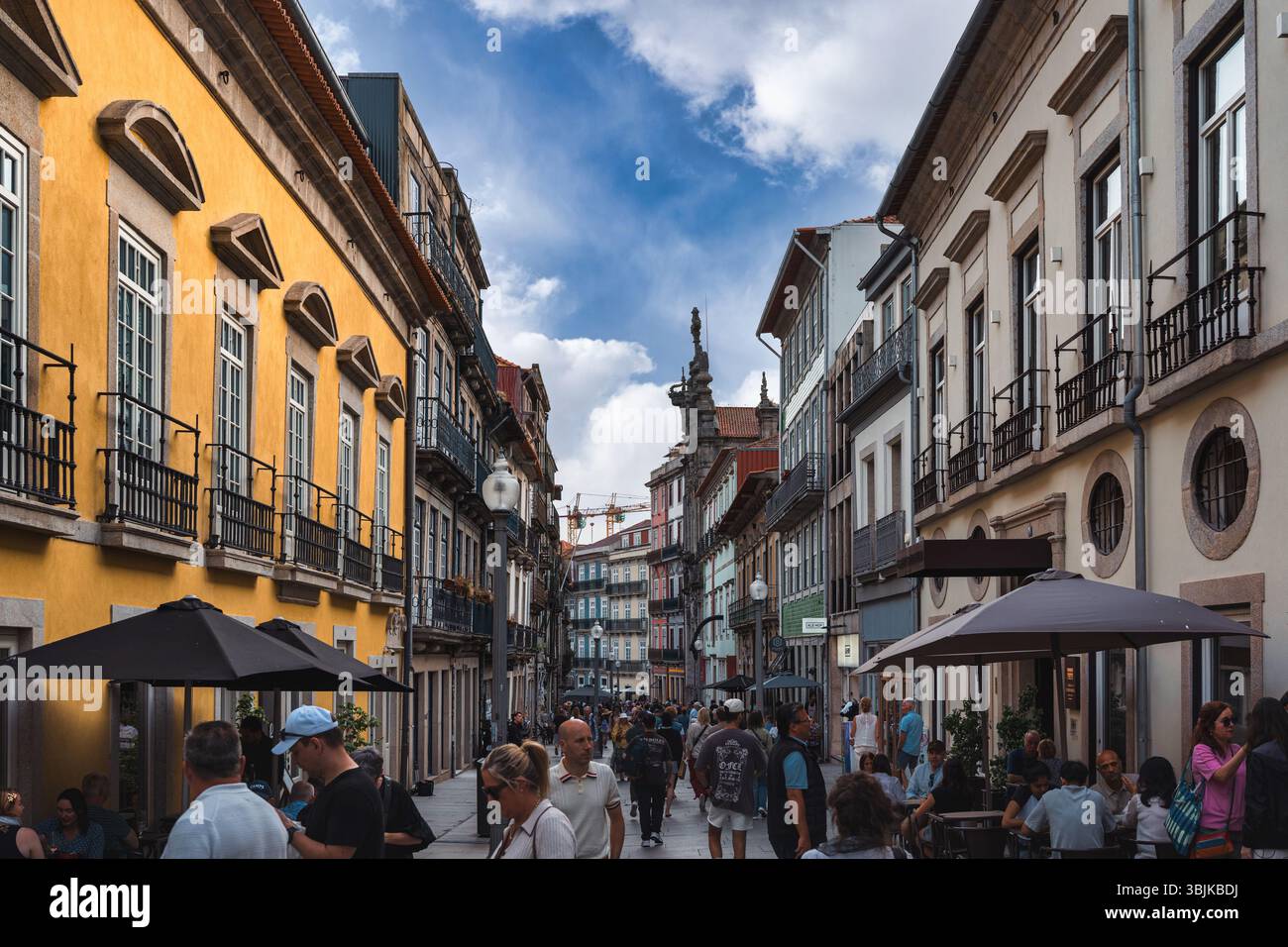 Vivace scena di strada con gente che cammina e cena tra i colorati edifici storici, catturando l'atmosfera vibrante di Porto, Portogallo - 11 giugno 2025 Foto Stock