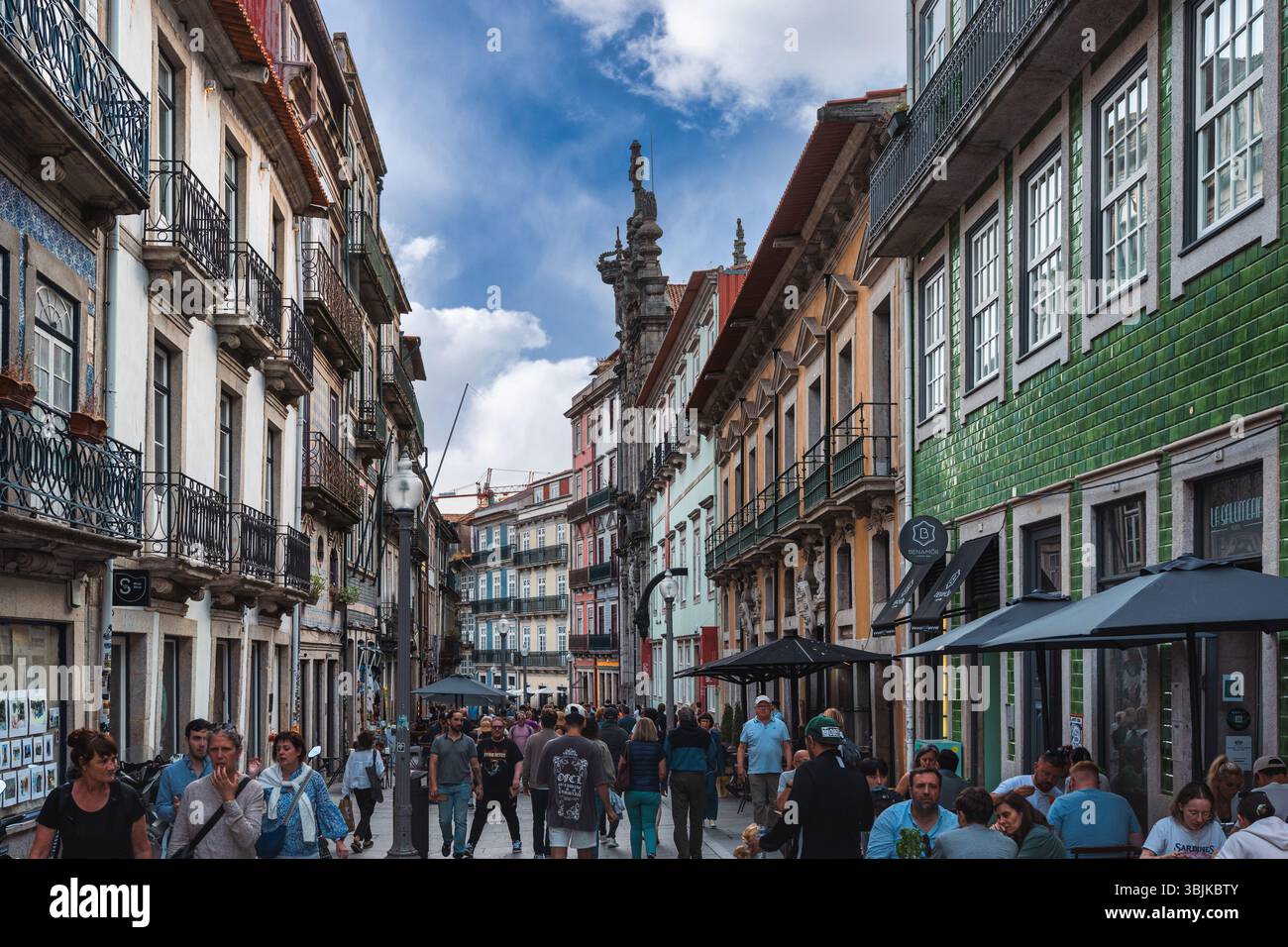 Vivace scena di strada con persone che camminano tra colorati edifici storici e caffetterie nel cuore di Porto, Portogallo - 11 giugno 2025 Foto Stock