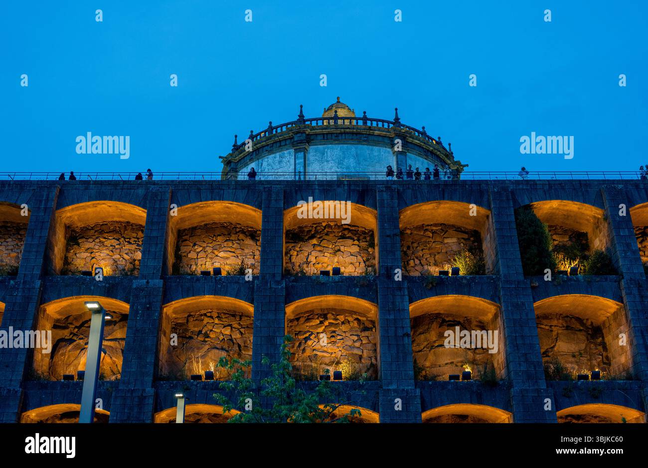 Vista notturna degli archi illuminati e della storica cupola del Monastero di Serra do Pilar, un sito UNESCO, con un vivace cielo blu. Vila Nova de Gaia, Portogallo - 11 giugno 2025 Foto Stock