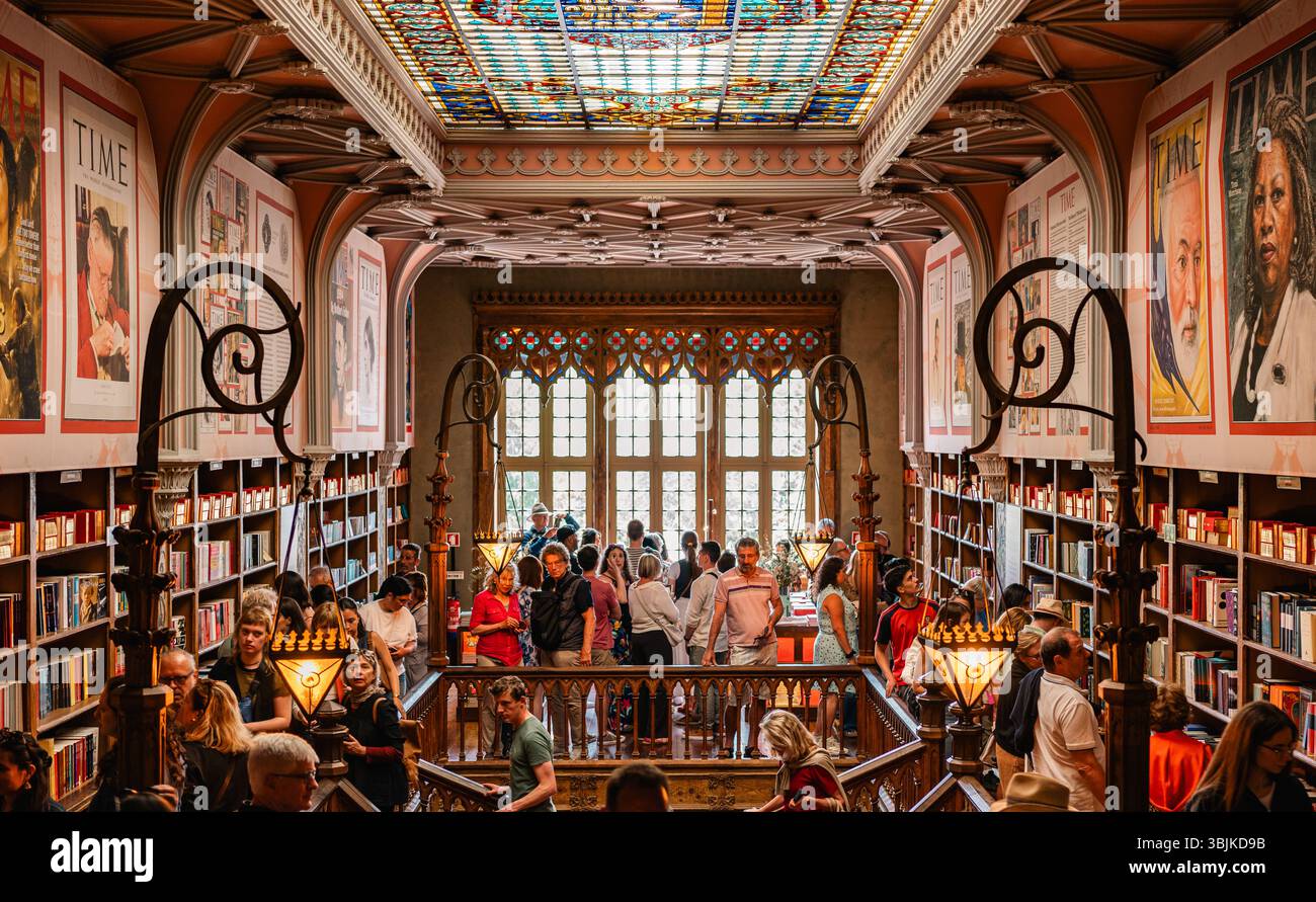 I turisti esplorano la storica libreria Livraria Lello, ammirando la sua architettura ornata, il soffitto in vetro colorato e l'atmosfera letteraria. Porto, Portu Foto Stock