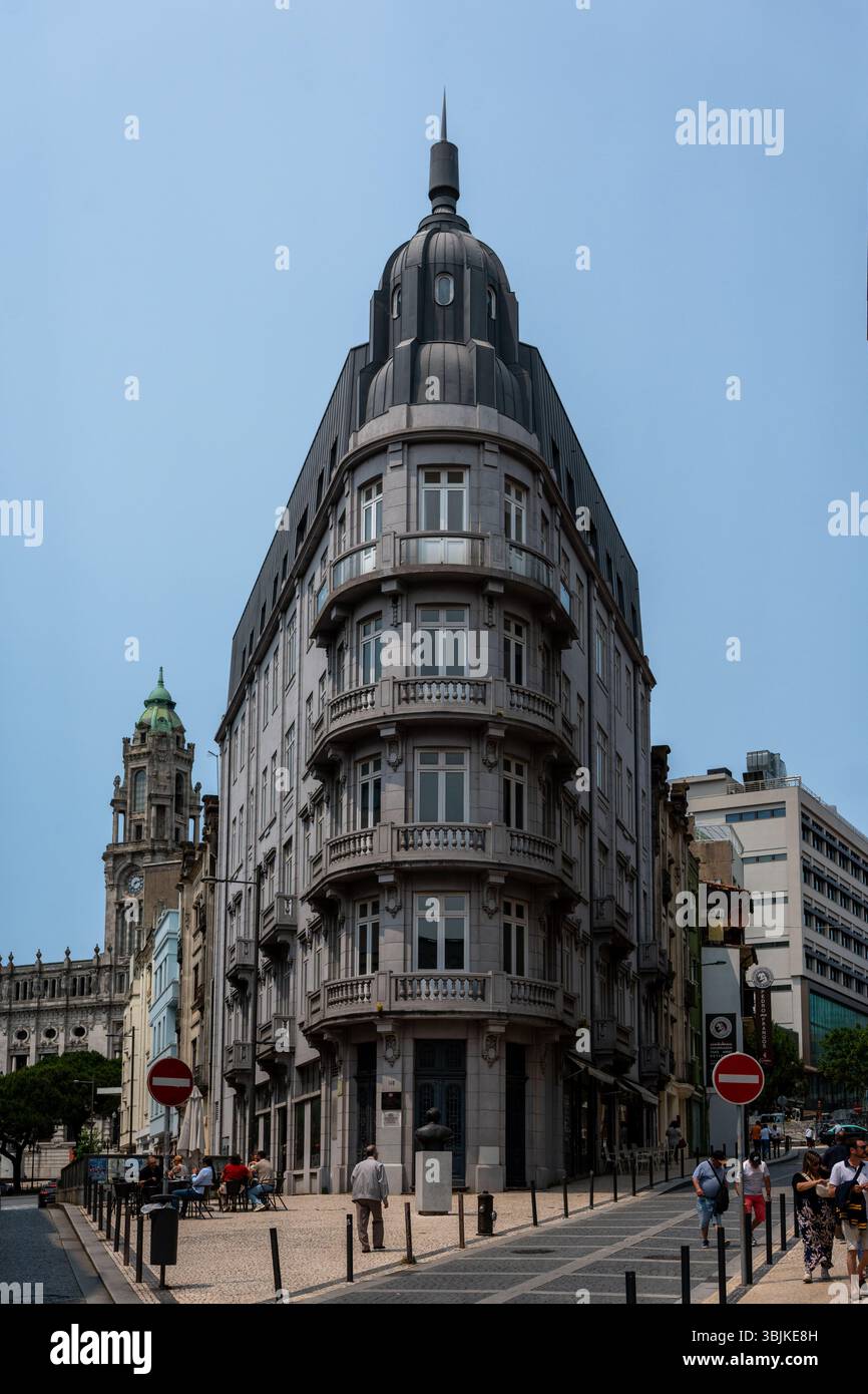 Splendida vista dell'iconico edificio in stile flatiron con architettura ornata e vivace vita di strada nel centro di Porto, Portogallo - 11 giugno 2025 Foto Stock