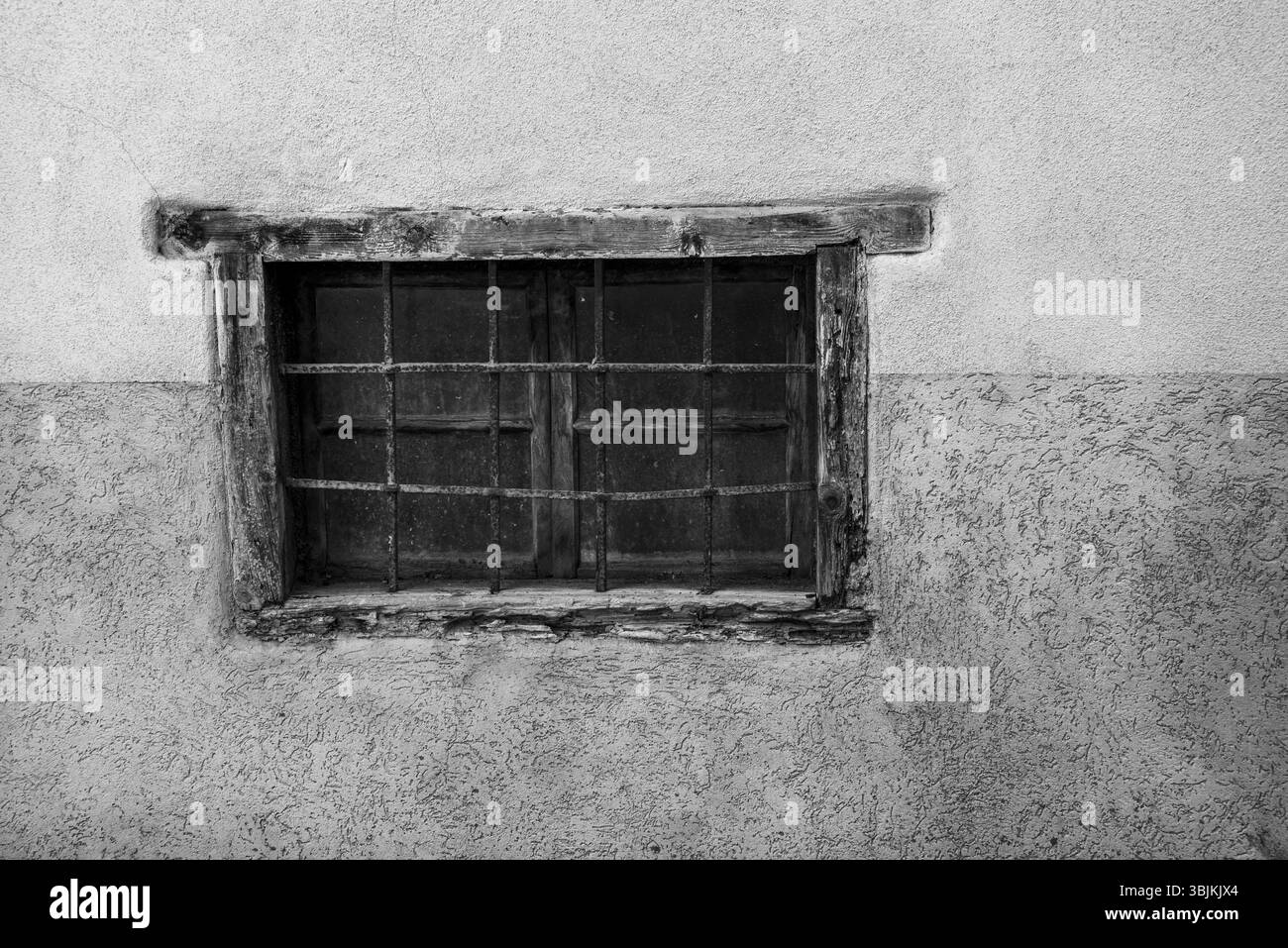 finestra con ringhiera arrugginita e vecchia struttura in legno con parete bianca Foto Stock