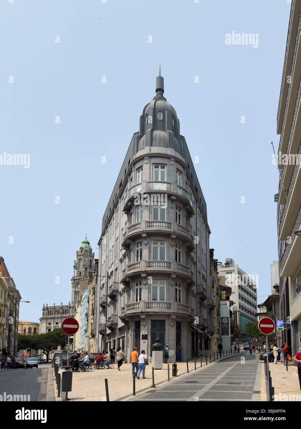 Iconico edificio in stile flatiron con architettura ornata e vivace vita di strada nel centro di Porto, Portogallo - 11 giugno 2025 Foto Stock