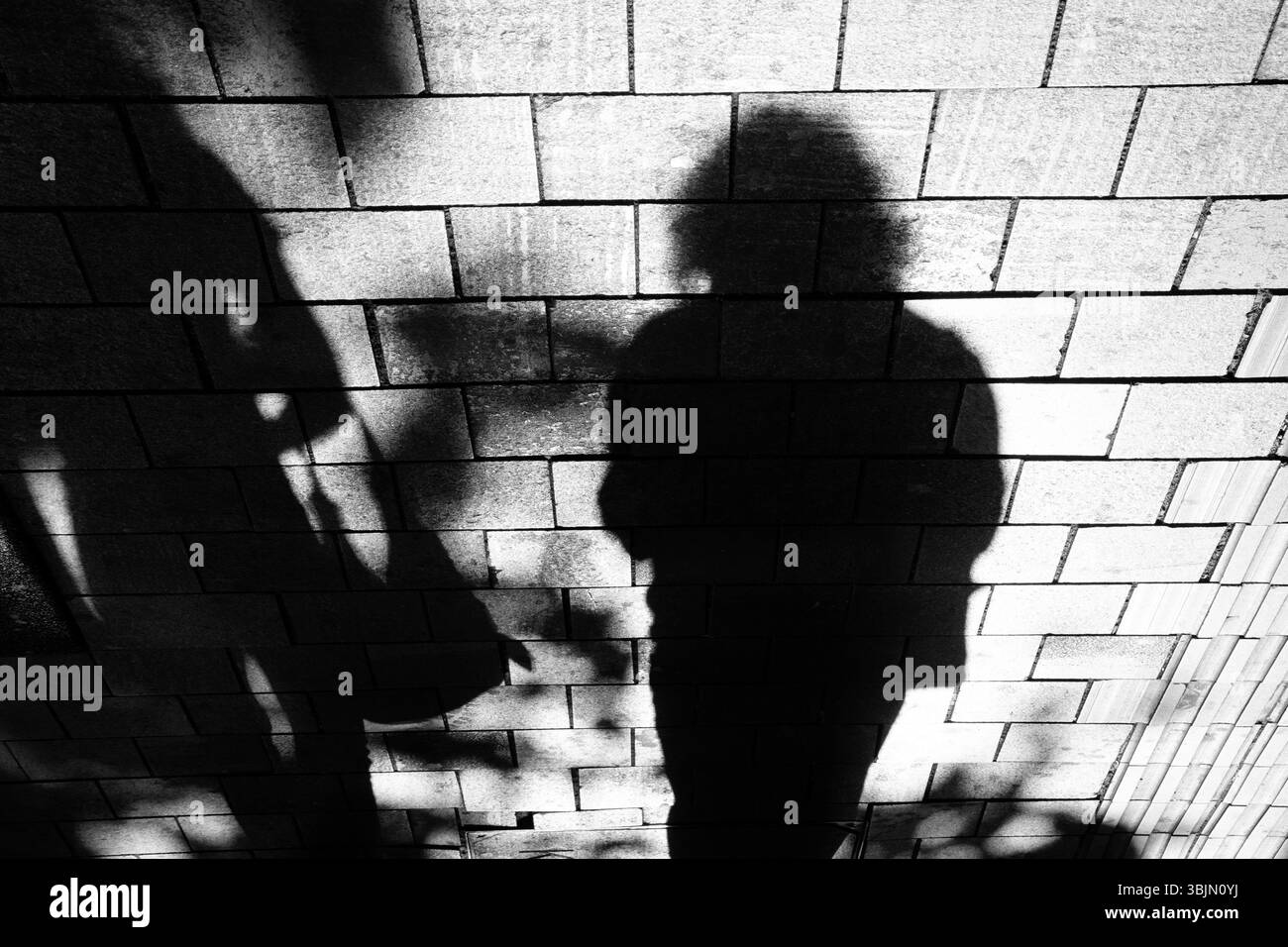 L'ombra di silhouette delle donne che camminano lungo la strada della città marciapiede in bianco e nero a contrasto elevato Foto Stock