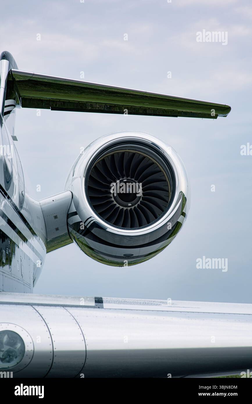 Motore jet e coda a T di un lussuoso business jet Gulfstream sotto cieli parzialmente nuvolosi. Fusoliera lucidata e dettagli della turbina chiaramente visibili. Foto Stock
