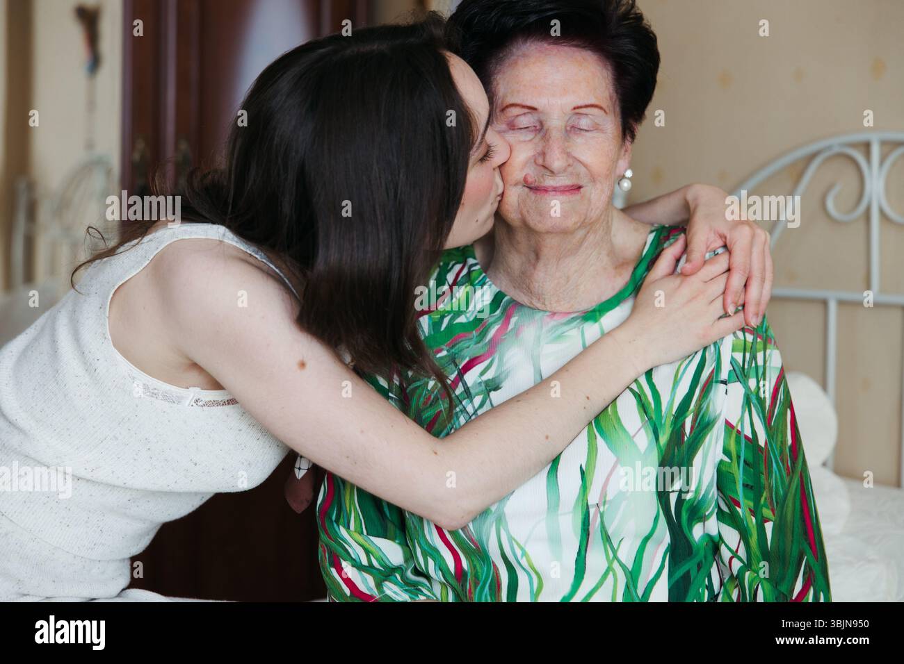Bacio emozionale e abbraccio tra una donna anziana e sua nipote Foto Stock