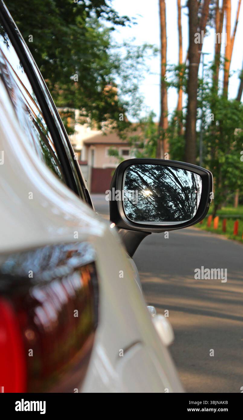 Gli alberi che si riflettevano in uno specchio laterale dell'auto rimasero su una strada rurale di fronte al cottage Foto Stock Gli alberi che si riflettevano in uno specchio laterale dell'auto rimasero su una strada rurale di fronte al cottage Foto Stock