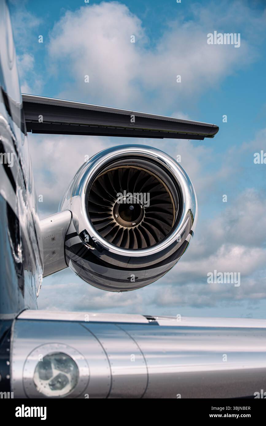 Motore jet e coda a T di un lussuoso business jet Gulfstream sotto cieli parzialmente nuvolosi. Fusoliera lucidata e dettagli della turbina chiaramente visibili. Foto Stock