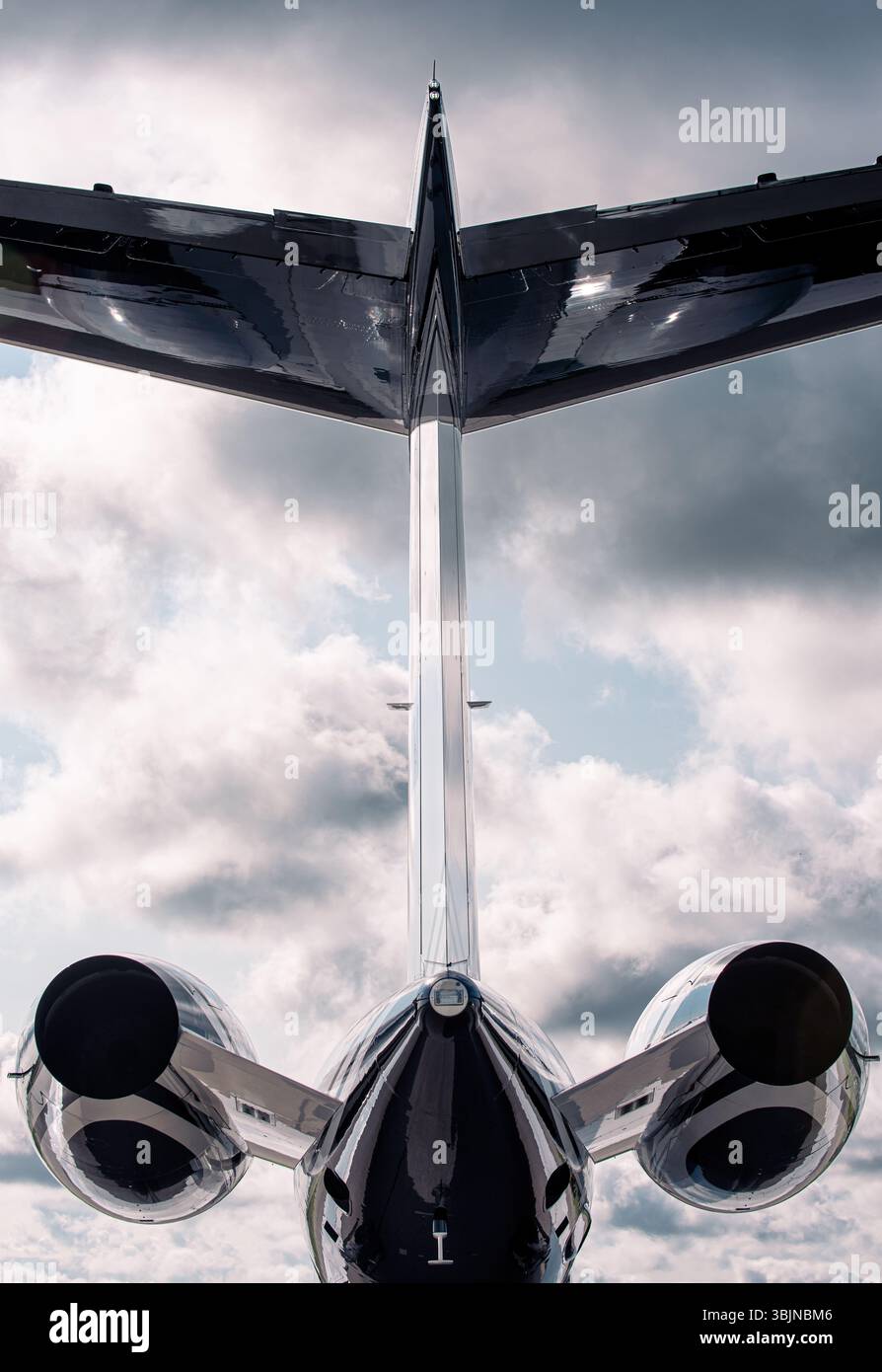 Vista posteriore del lussuoso jet privato con due motori e design a T-TAIL, fotografato da terra guardando verso l'alto contro il cielo nuvoloso. Foto Stock