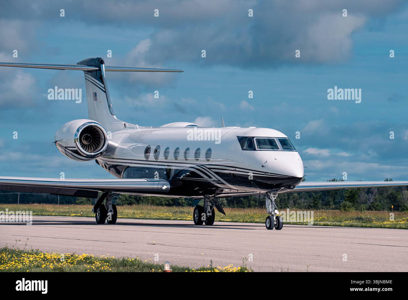 Lussuoso jet privato Gulfstream che ruba sulla pista dell'aeroporto, fotografato in una giornata luminosa con cielo blu e nuvole sparse. Foto Stock