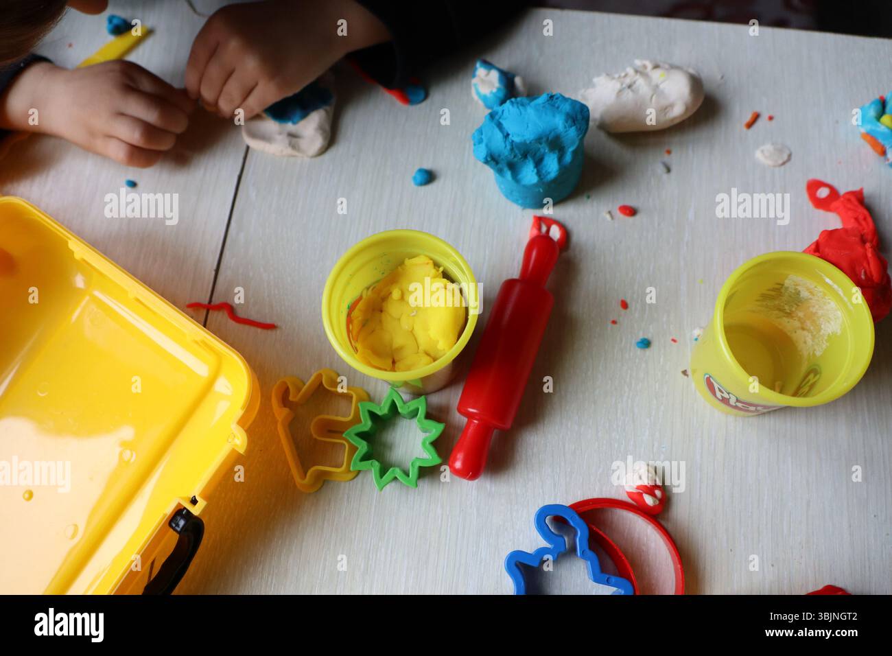 I bambini si impegnano con gioia in vivaci attività creative utilizzando colorate argilla da modellare e una varietà di strumenti Foto Stock