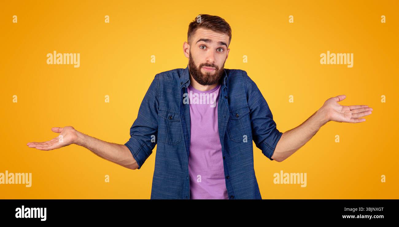 Non lo so. Bel ragazzo caucasico che si infrange le spalle, sentendosi perplesso o incerto su sfondo arancione studio Foto Stock