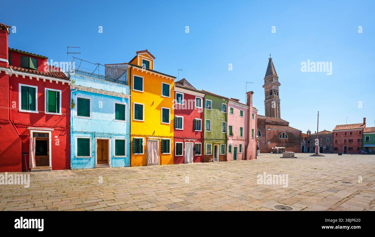 La piazza principale dell'isola di Burano, le case colorate e la chiesa con il suo campanile pendente. Venezia, Veneto, Italia Foto Stock